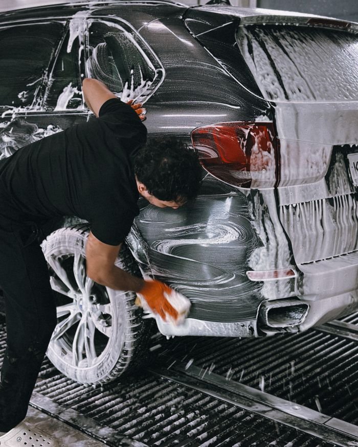 The Art of Drawing Readers In: Your attractive post title goes here A person meticulously washing a car at a car wash using soap and a sponge.