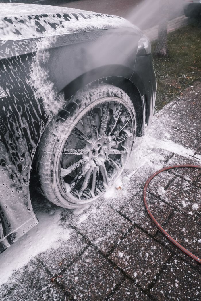 Mastering the First Impression: Your intriguing post title goes here Close-up of a luxury car wheel being thoroughly washed with foam outdoors.
